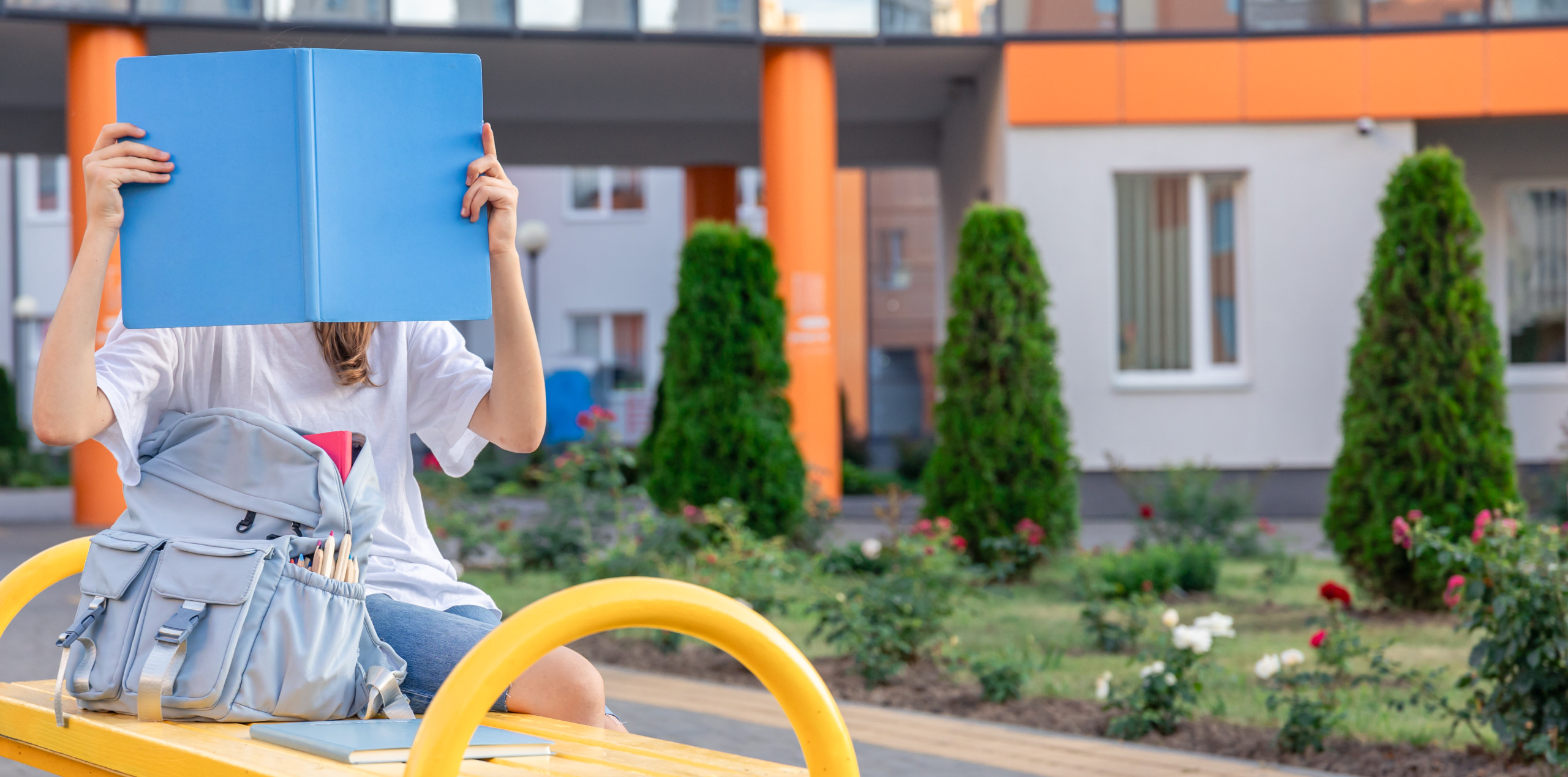 girl-with-blue-notebook-covers-her-face-background-school-scaled.jpg